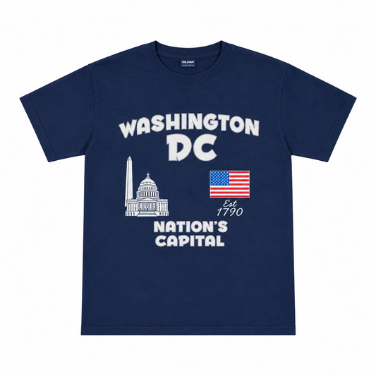 A navy blue short-sleeve t-shirt laid flat on a wooden floor, featuring a white graphic that reads 'WASHINGTON DC' with 'NATION'S CAPITAL' and an American flag.